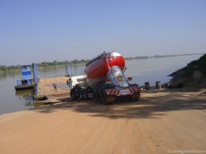 Loaded fuel trucks load the ferry to cross the Mekong