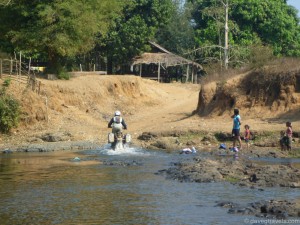 Dean and his KTM 950 SE powering out of a river in Laos